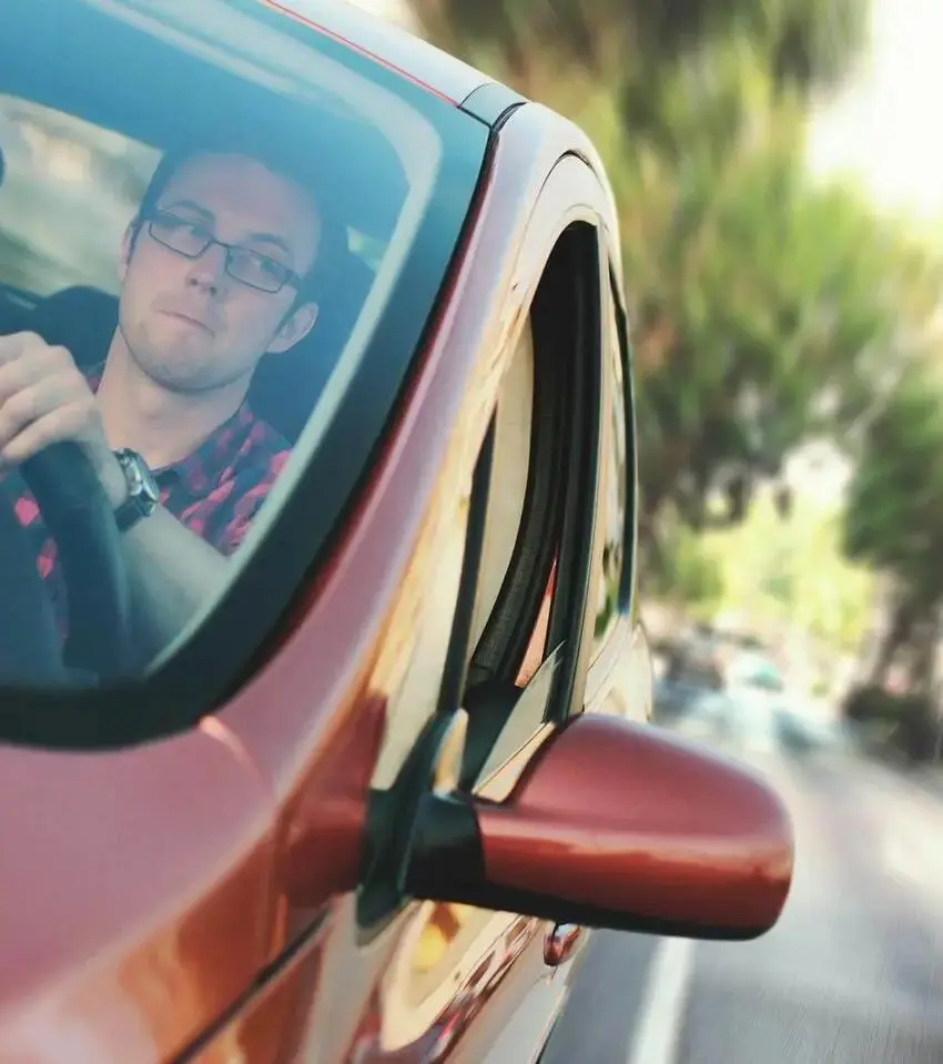 homem dirigindo veículo, olhando retrovisor, representando Bradesco Seguro Auto