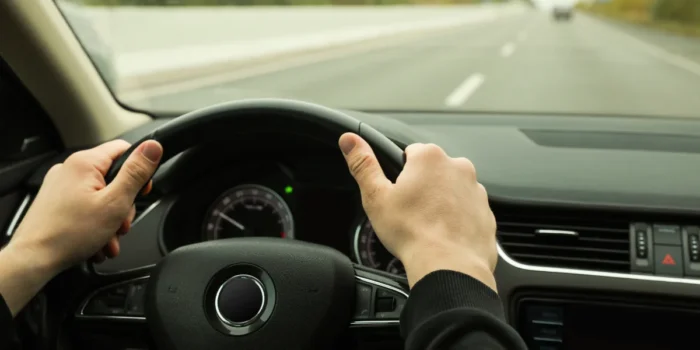 Duas mãos em um volante representando direção segura.