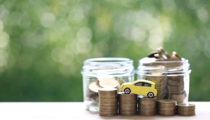 Dicas para Economizar no Seguro Auto São José SC representado por um carrinho com potes de moeda atrás.