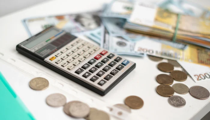 Quanto Custa uma Honda SH 300i e Como o Valor Afeta o Seguro representado por dinheiro, uma calculadora e moedas.