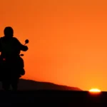 Seguro Honda SH 150i representado por uma foto de uma moto com uma pessoa no pôr do sol.