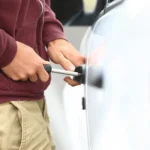 carro financiado roubado com seguro sendo representado por um homem tentando abrir a porta de um carro