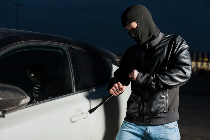 Criminoso tenta arrombar um carro branco.