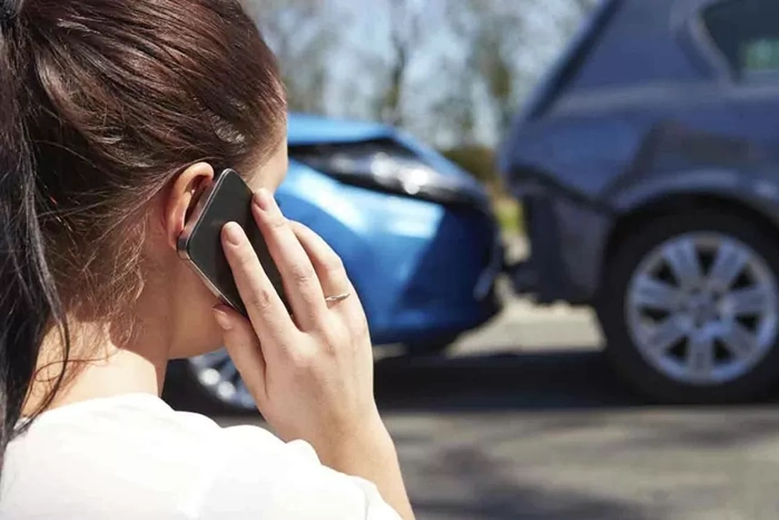 Acidente de carro, com colisão traseira. Mulher fala ao telefone. Falando sobre seguro auto contra terceiros.