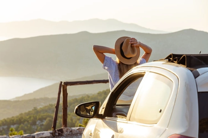 Mulher faz pausa em viagem de carro para admirar a paisagem. Explicando o que é carta verde.