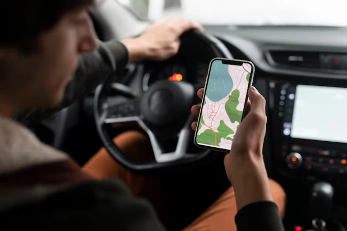 Motorista observa sinal de rastreamento em seu celular enquanto dirige um carro. Falando sobre rastreador com seguro.