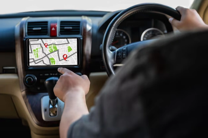 Homem dirige carro enquanto usa um GPS. Falando sobre rastreador com seguro.