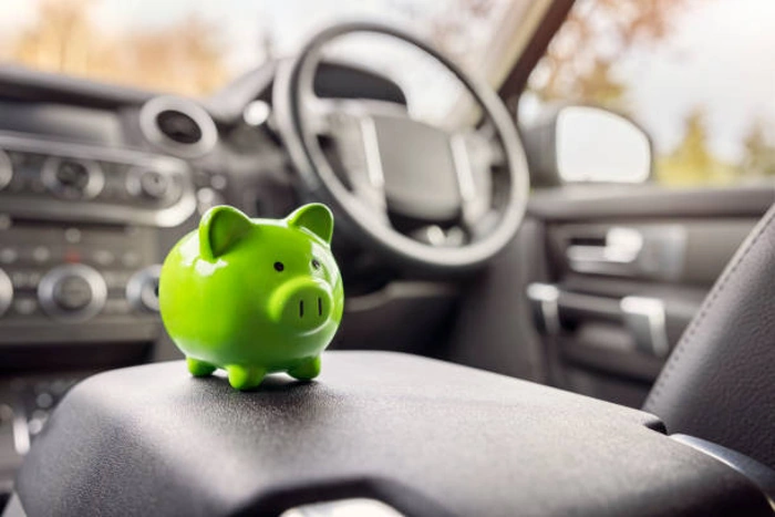 Cofre em formato de porquinho na cor verde no interior de um carro. Explicando qual o melhor seguro para carros e mais barato.