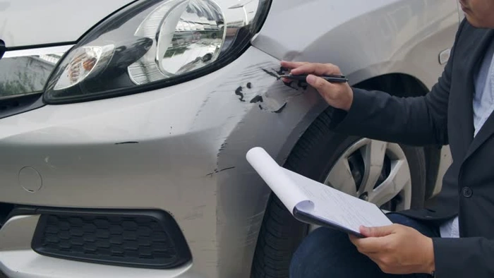 Técnico analisa avaria em veículo. Falando sobre o valor do seguro carros.