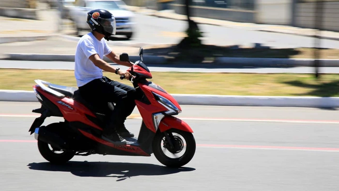Homem pilota motoneta em via pública. Explicando a partir de quantas cilindradas precisa de habilitação.