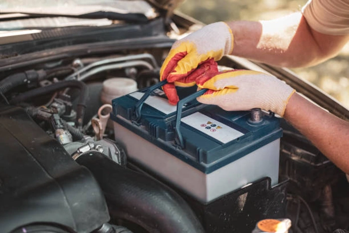 Profissional segurando bateria automotiva. Falando sobre luz da bateria acendendo no painel do carro.