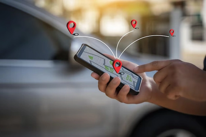 Pessoa analisa celular com app de rastreamento ativo. Há sinais gráficos que indicam posição na imagem. Falando sobre como funciona o mini rastreador veicular.