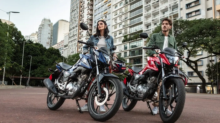 Modelos posam ao lado de duas Honda Fan 160 em um ambiente urbano. Falando sobre  o seguro fan 160.