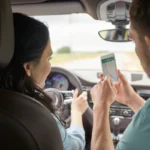 Motorista e seu carona observam dados de um rastreador veicular por um celular. Falando sobre seguro de carro com rastreador.