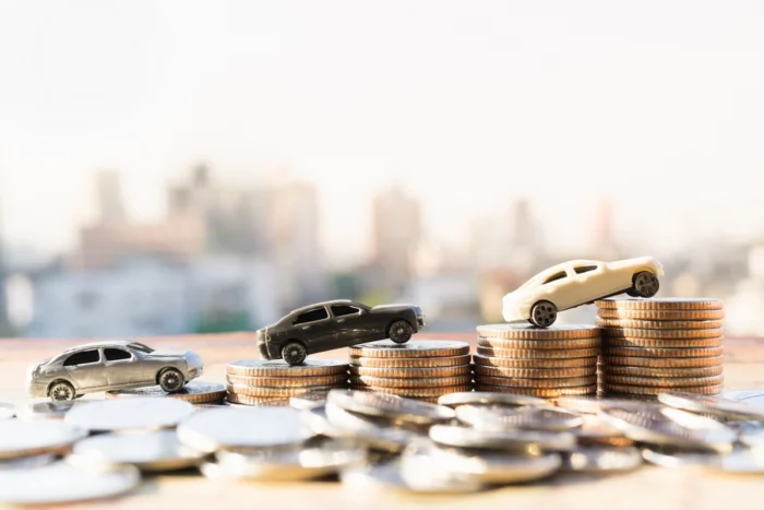 Miniaturas de carros sobre pilhas de moedas. Falando sobre seguro mais barato para carro.