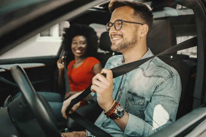 Motorista de app sorridente com sua passageira também alegre. Falando sobre seguro para carro de aplicativo.