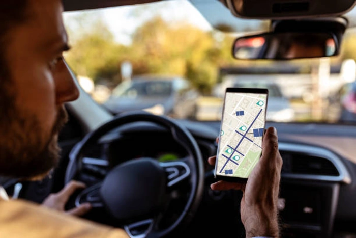 Motorista observa rota em seu celular enquanto dirige. Falando sobre seguro de carro com rastreador.