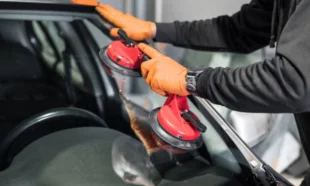 Profissional com instrumento para instalação de para-brisas. Falando sobre cobertura de vidros no seguro auto.