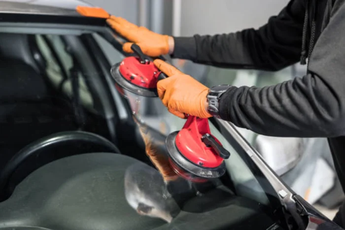 Profissional com instrumento para instalação de para-brisas. Falando sobre cobertura de vidros no seguro auto.