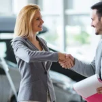 Homem e mulher fecham a negociação de um carro. Falando sobre como negociar um carro.