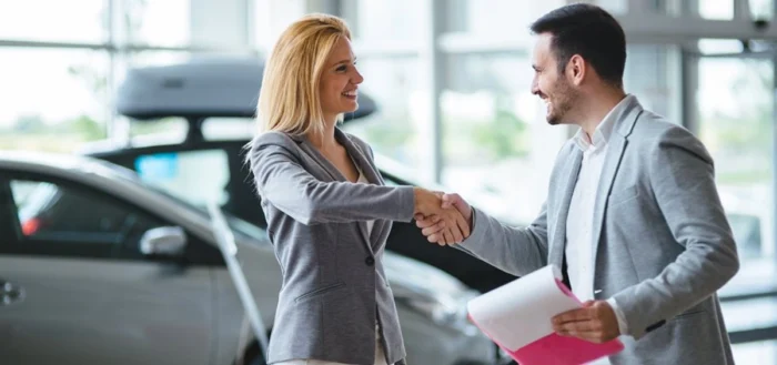 Homem e mulher fecham a negociação de um carro. Falando sobre como negociar um carro.