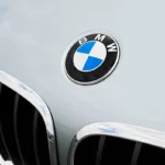 Zoom em frente de carro da BMW, pegando a logomarca da montadora. Falando sobre o seguro bmw.